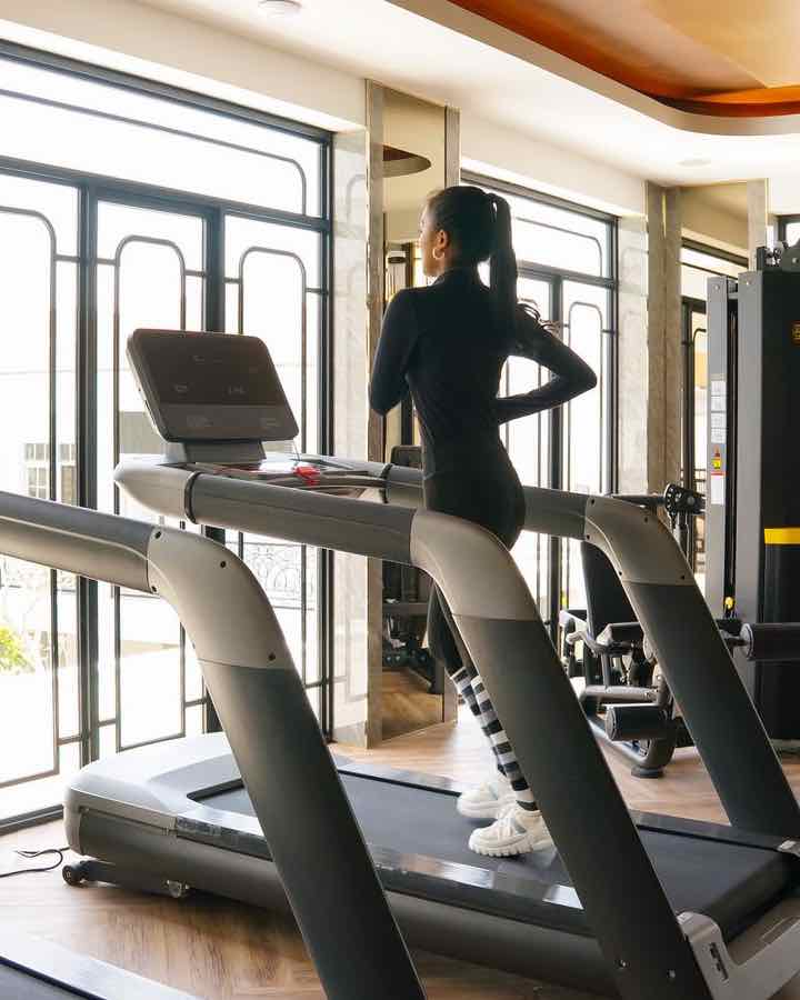 Clienta entrenando en una cinta de correr en un gimnasio con luz natural